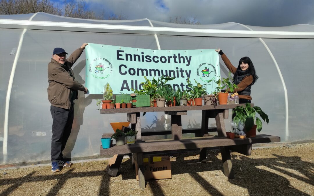 Members of the allotments holding a banner behind a table full of plants